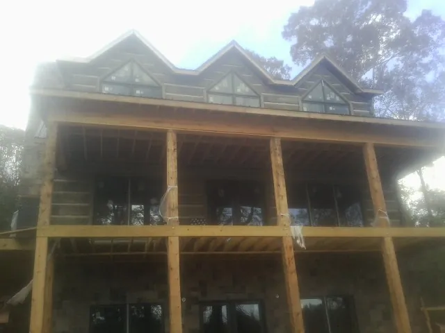 Dormers and porch framing on a large log home under construction — Roof Coating work by our crew in Gladewater