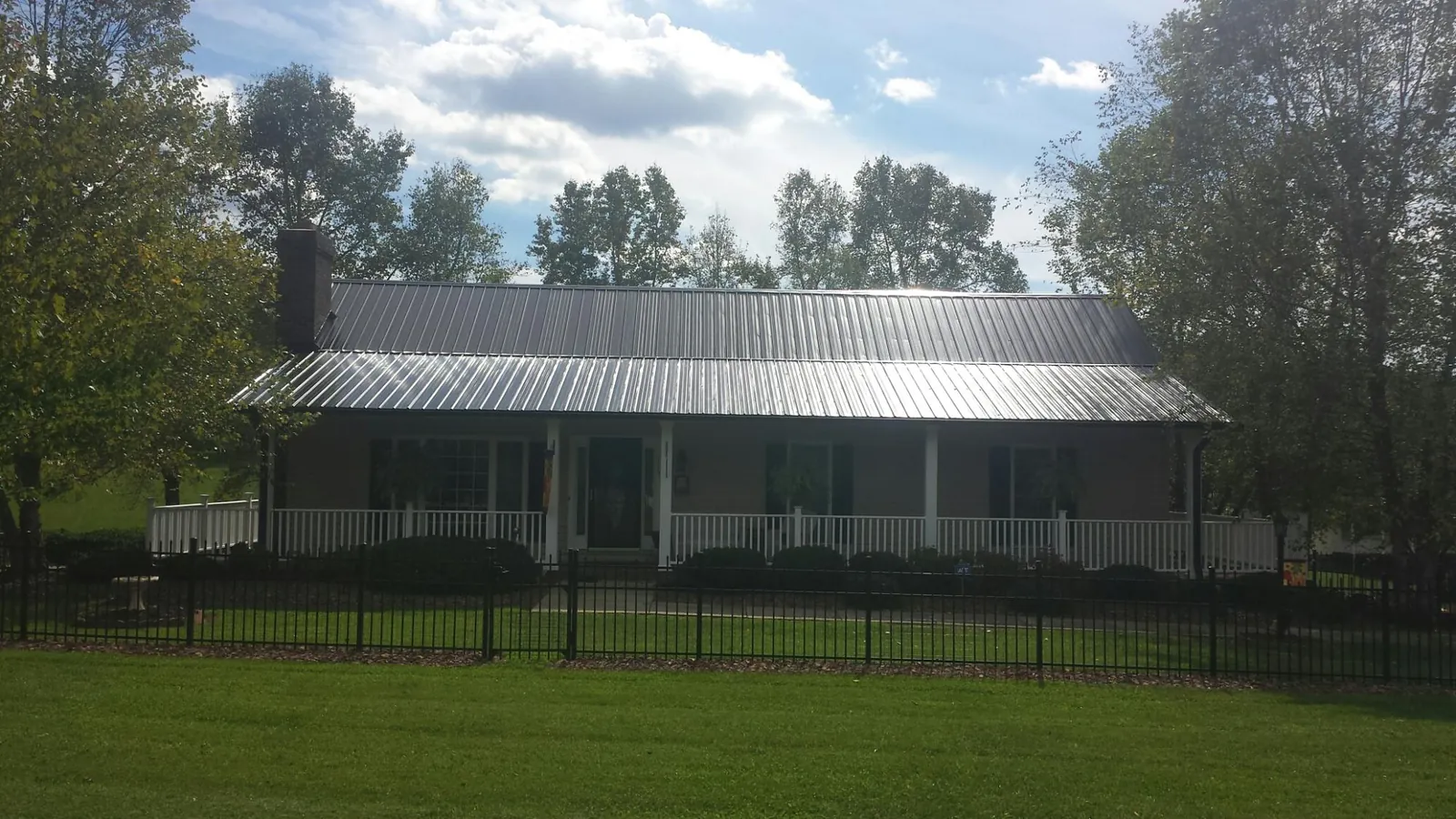 Gray metal roof on a brick ranch with a full width front porch — Gutter Guard Installation work by our crew in Gladewater