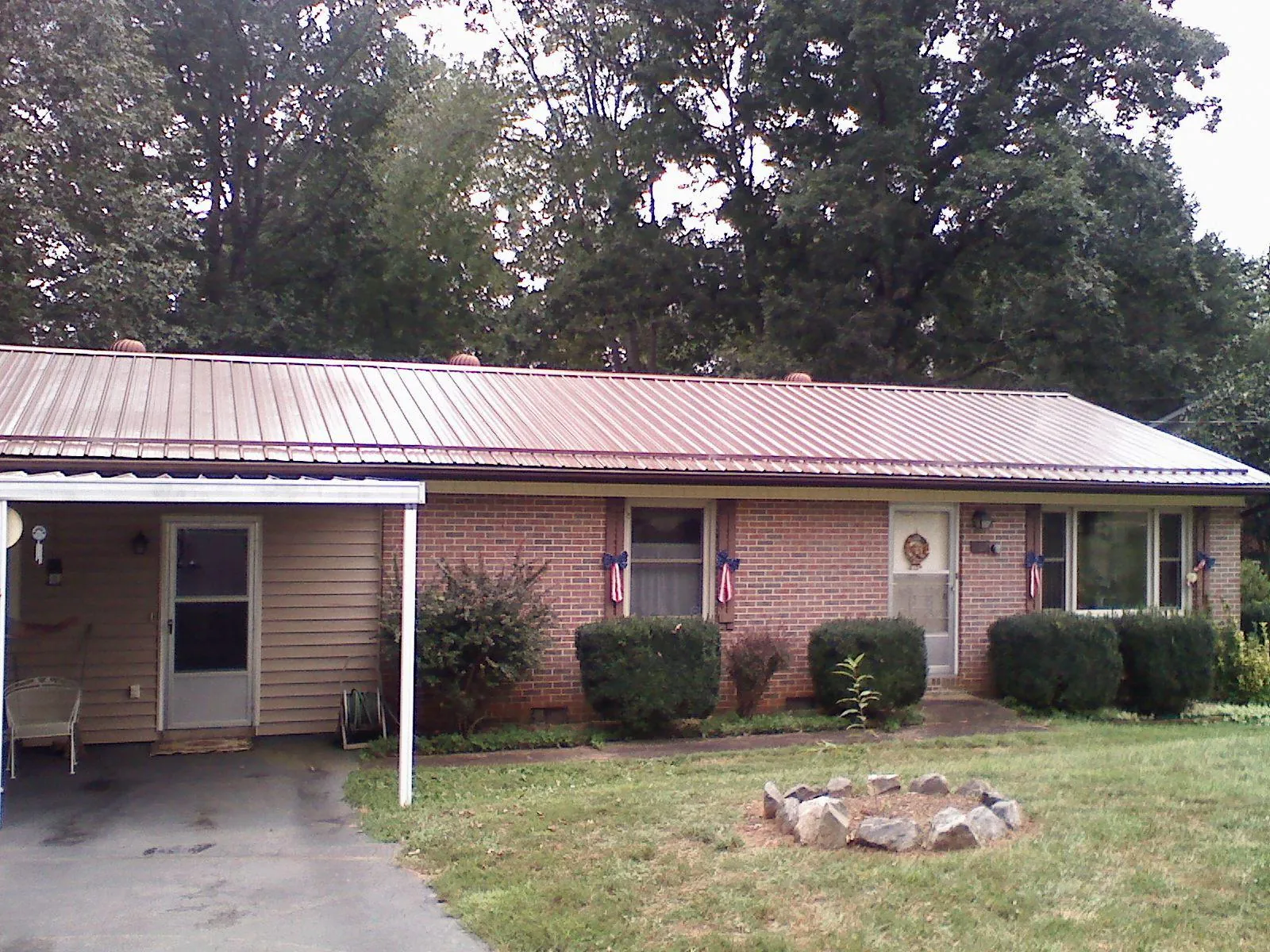 Bronze metal roof and carport on a brick ranch home — Roof Repair work by our crew in Gladewater