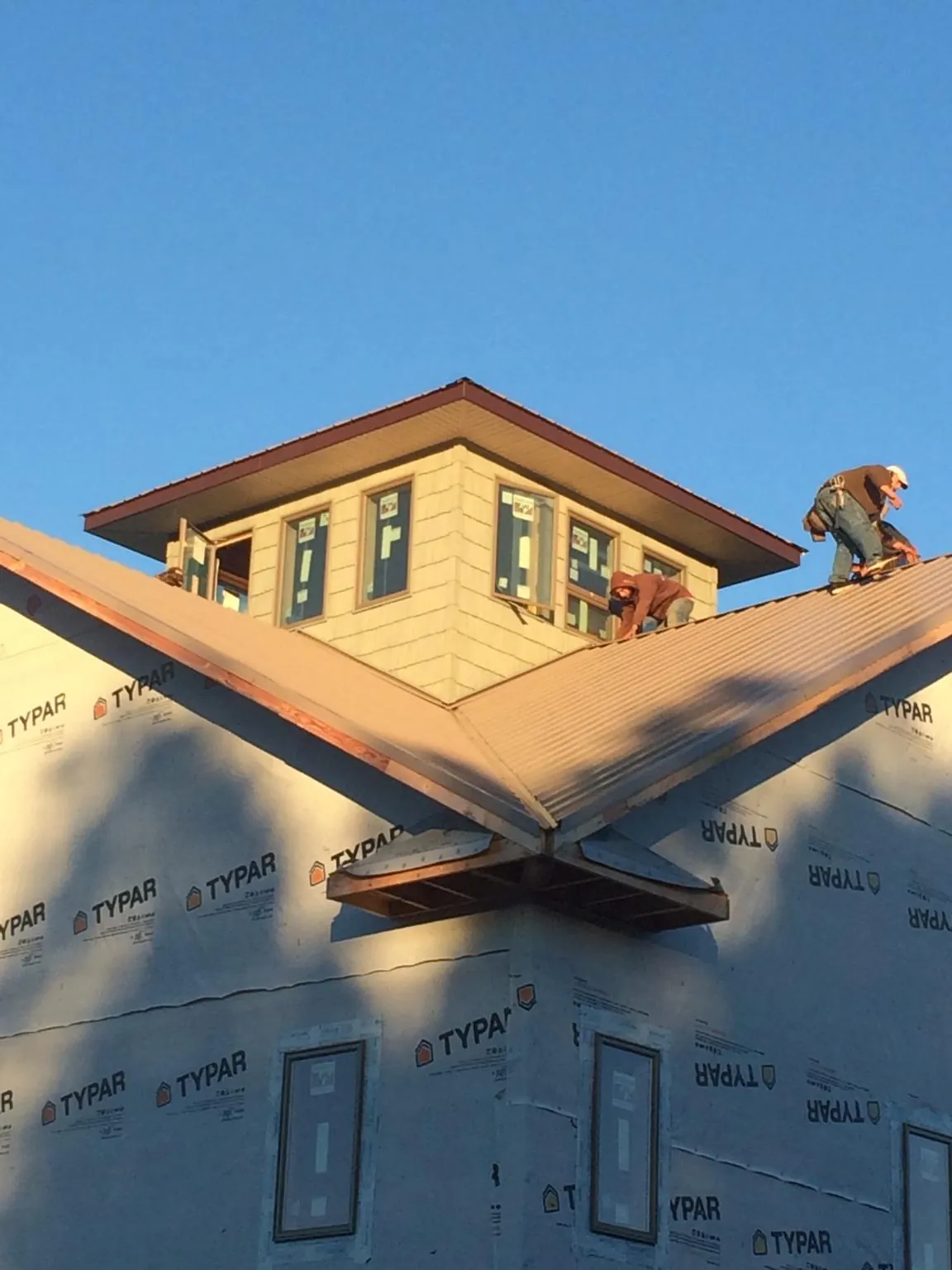 Roofers working around a rooftop cupola on a new metal roof at sunset — Roof Waterproofing in Gladewater by Roofing Brothers